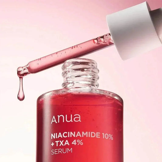 Pipette chargée de sérum rose au-dessus du flacon ouvert du sérum Anua Niacinamide 10 % + TXA 4 %