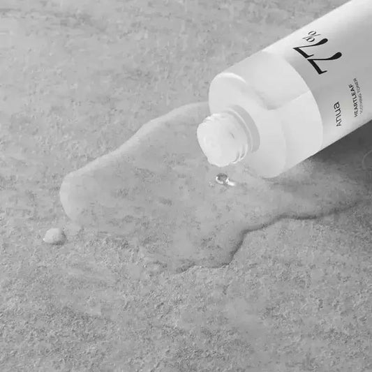 Texture liquide transparente du toner Anua Heartleaf 77 % versée sur une surface grise