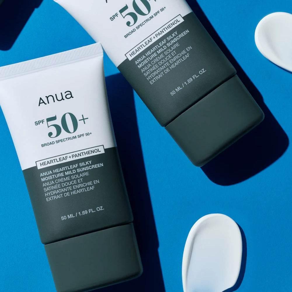 Deux tubes de crème solaire Anua Heartleaf Silky Moisture et touches de crème blanche sur fond bleu