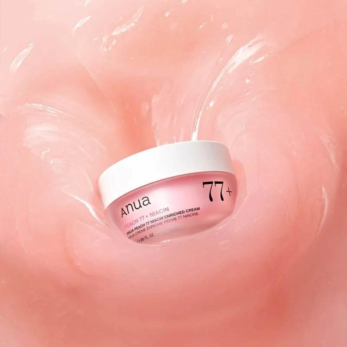 Pot de la crème Anua Peach 77 Niacin posé au creux d'une texture crème rosée