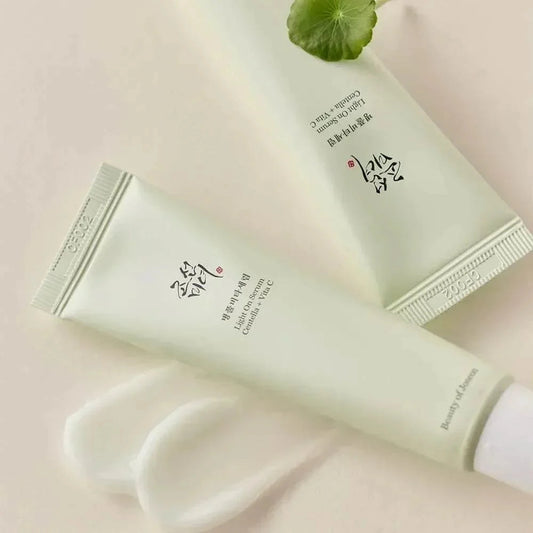 Deux tubes du sérum Beauty of Joseon Light On avec une traînée de texture blanche et une feuille