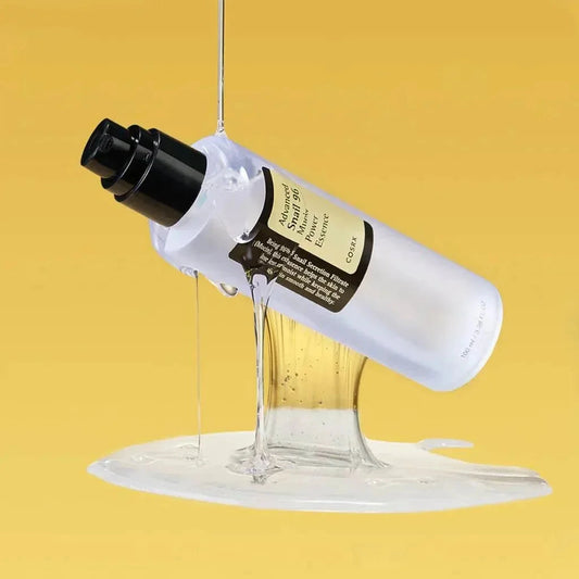 Flacon de l'essence COSRX Advanced Snail 96 renversé laissant couler une texture gel sur fond jaune