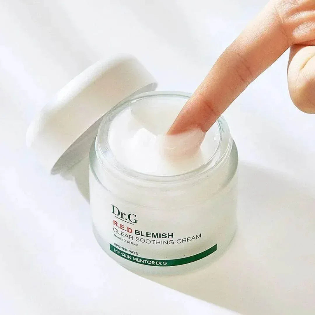 Doigt plongé dans le pot ouvert de la crème apaisante Dr.G R.E.D Blemish