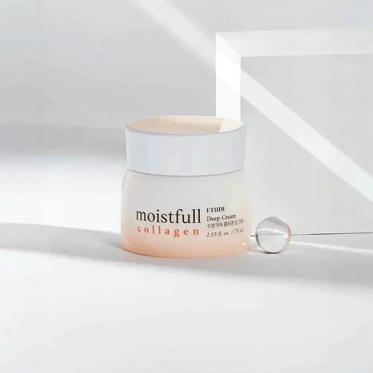 Pot de la crème ETUDE Moistfull Collagen Deep Cream et sphère en verre sur un socle blanc