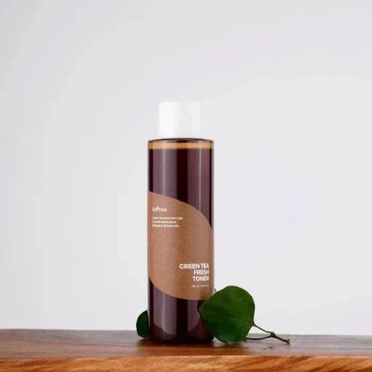Flacon du toner Isntree Green Tea Fresh posé sur une planche en bois avec des feuilles vertes