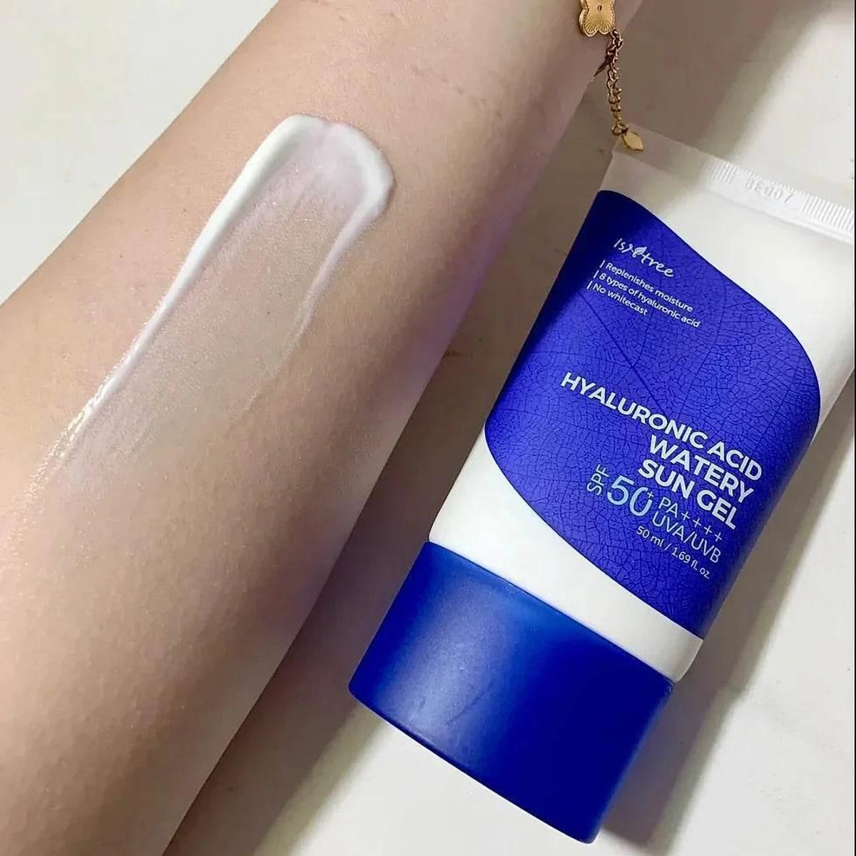 Trace de texture blanche de la crème solaire Isntree Watery Sun Gel étalée sur l'avant-bras, tube à côté