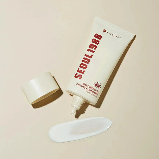 Tube ouvert de la crème solaire K-SECRET Seoul 1988 Sun à côté d'une trace de crème blanche