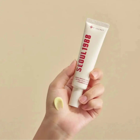 Main tenant le tube de la crème yeux K-SECRET Seoul 1988, noisette de crème jaune sur le doigt
