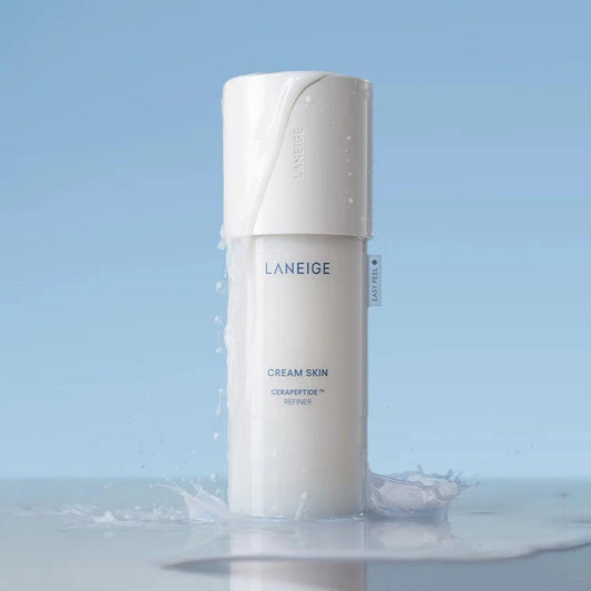 Flacon de la lotion LANEIGE Cream Skin Cerapeptide Refiner posé dans l'eau, fond bleu