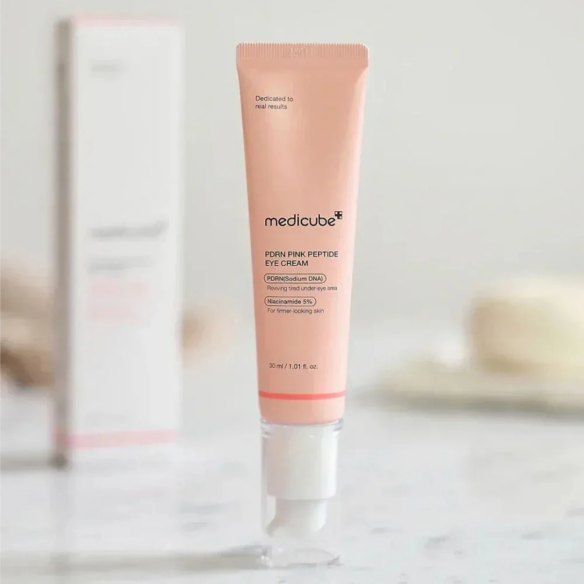 Tube de la crème Medicube PDRN Pink Peptide debout devant sa boîte sur un plan de marbre