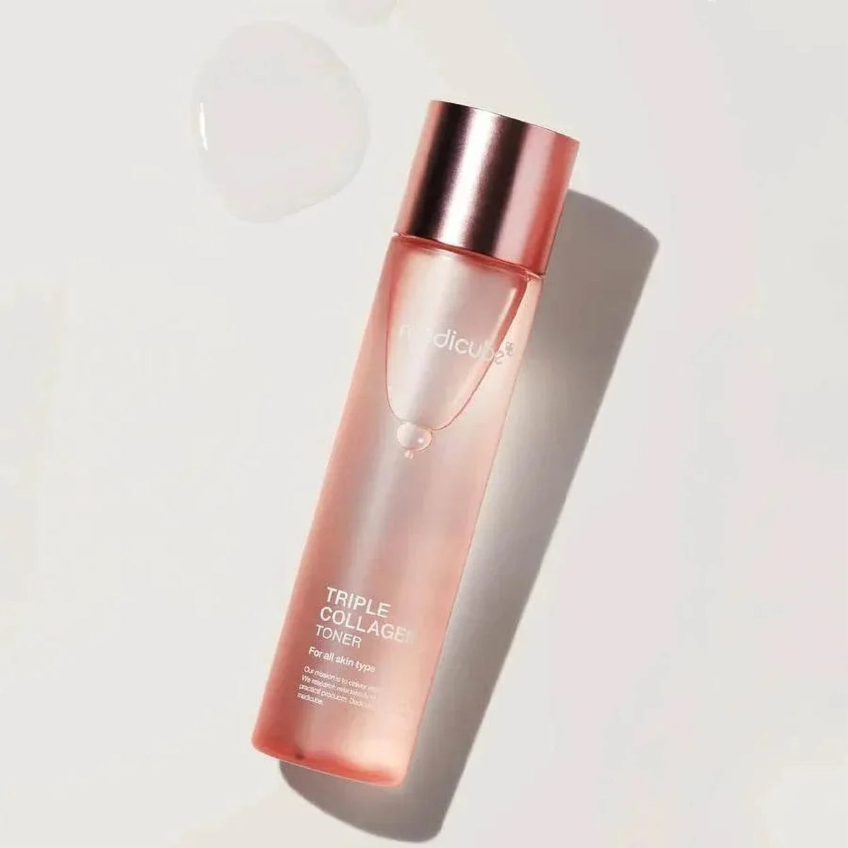 Flacon du toner Medicube Triple Collagen 4.0 et goutte de texture transparente sur fond gris clair
