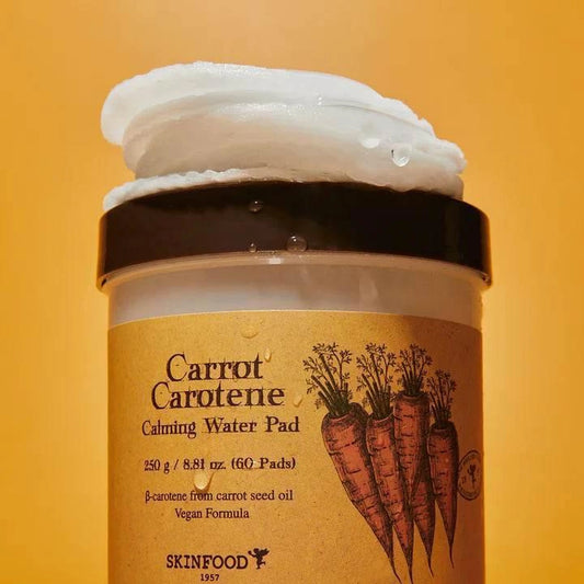 Pot des pads Skinfood Carrot Carotene débordant de pads imbibés sur fond orange