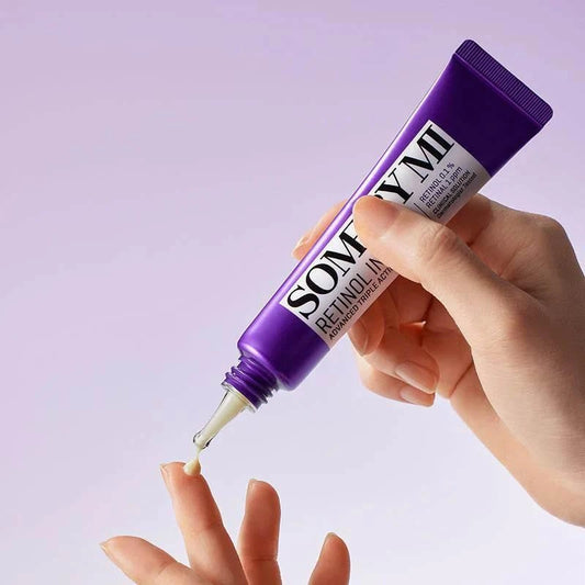 Main déposant la crème contour des yeux Some By Mi Retinol Intense sur le bout d'un doigt, fond lilas