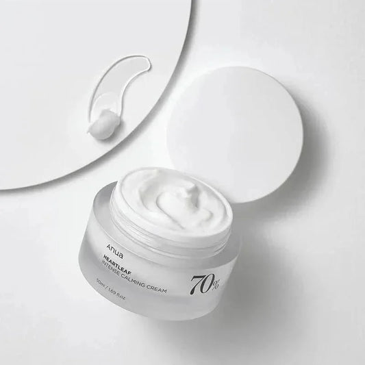 Pot ouvert de la crème Anua Heartleaf 70 avec une noisette de crème blanche à côté