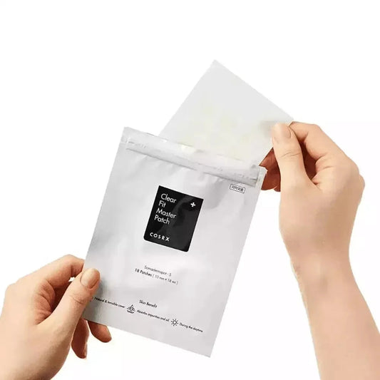Mains sortant la planche de patchs transparents du sachet COSRX Clear Fit Master Patch
