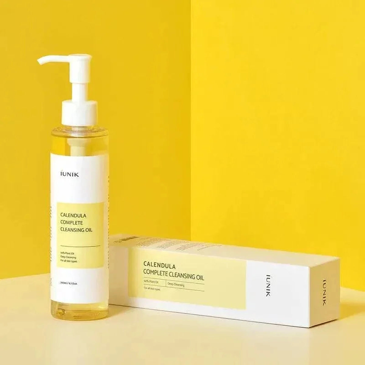 Huile démaquillante iUNIK Calendula Complete à côté de sa boîte sur fond jaune vif