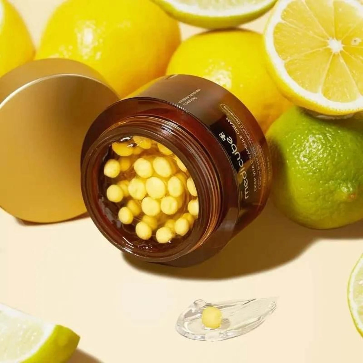 Pot ouvert de la crème Medicube Deep Vita C Capsule entouré de citrons jaunes et verts