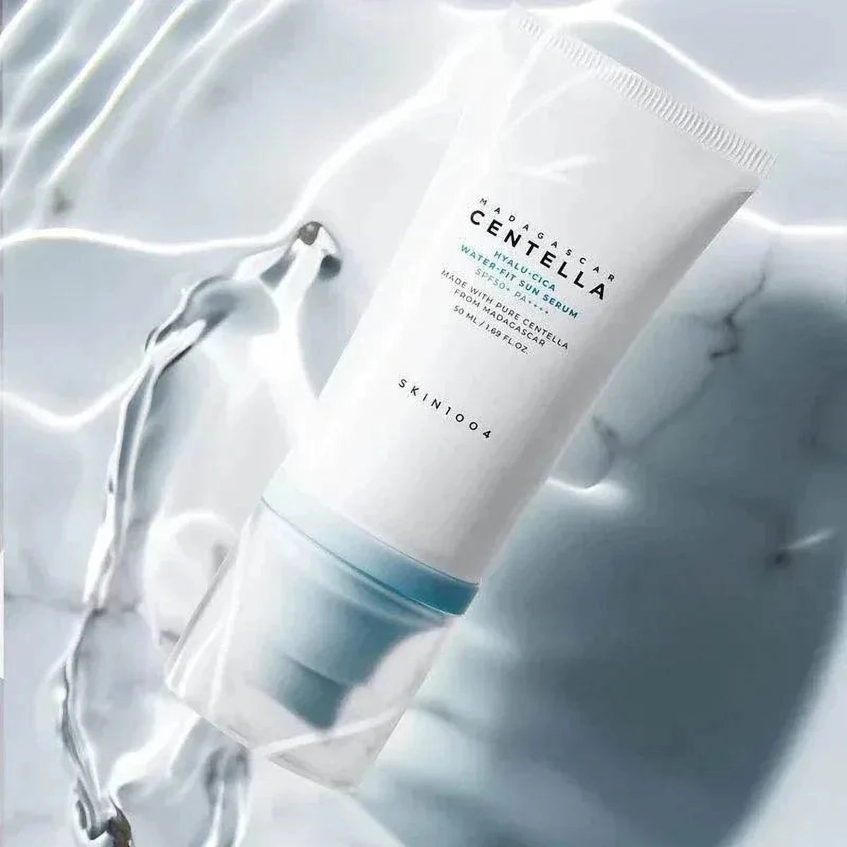 Tube du sérum solaire SKIN1004 Hyalu-Cica Water-Fit posé sur du marbre dans une eau claire