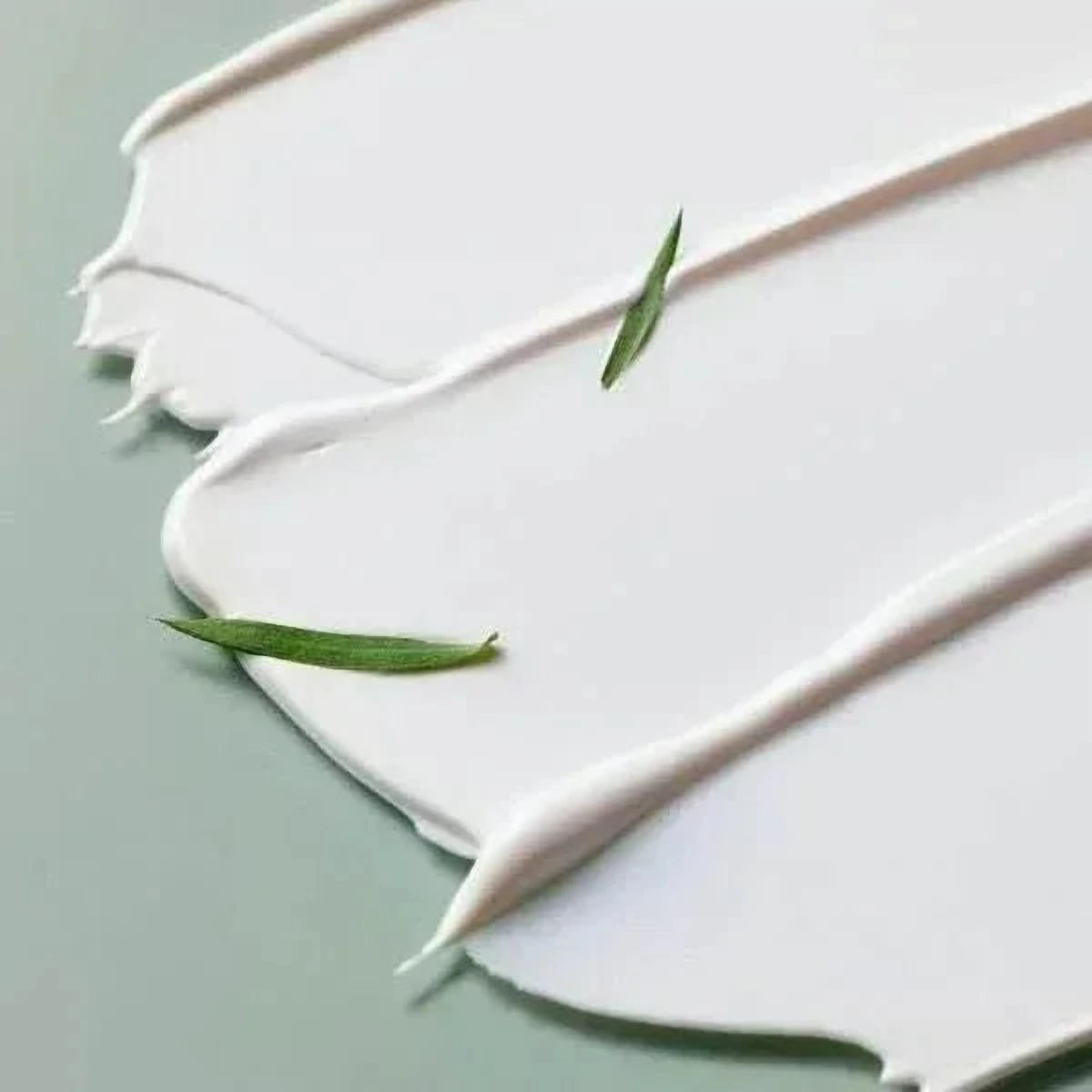 Texture crème blanche de la crème solaire Some By Mi Truecica avec des feuilles fines
