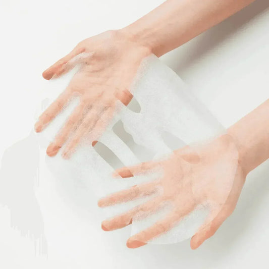 Deux mains déployant la feuille blanche du masque en tissu Some By Mi Real AHA BHA PHA Calming Care