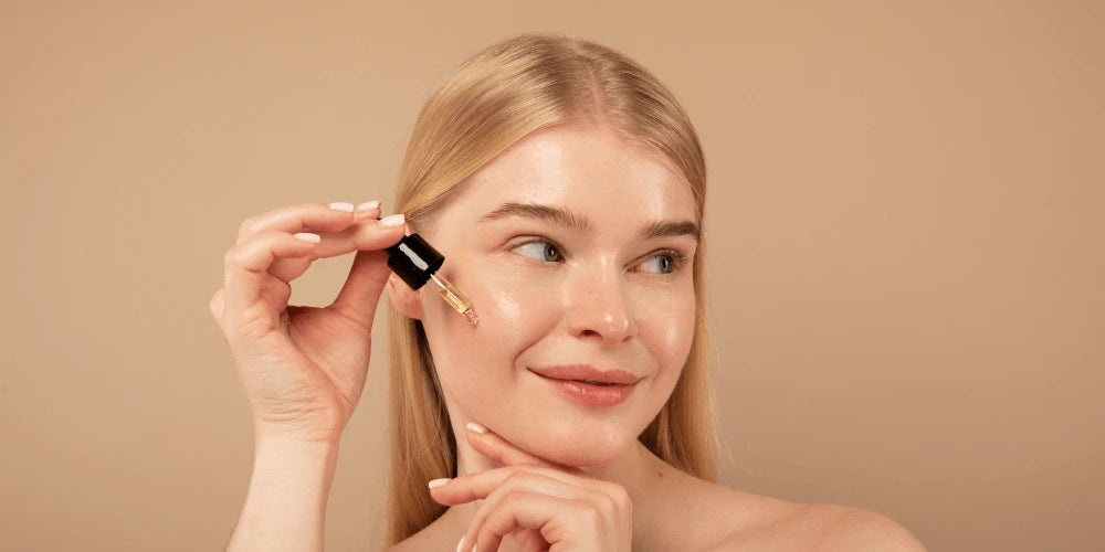 Femme appliquant une ampoule de sérum hydratant sur la joue pour un teint lumineux.