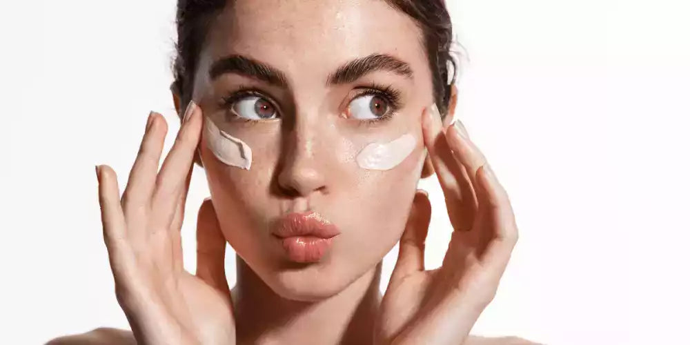 Jeune femme appliquant des touches de crème contour des yeux pour réduire les cernes et hydrater le regard.