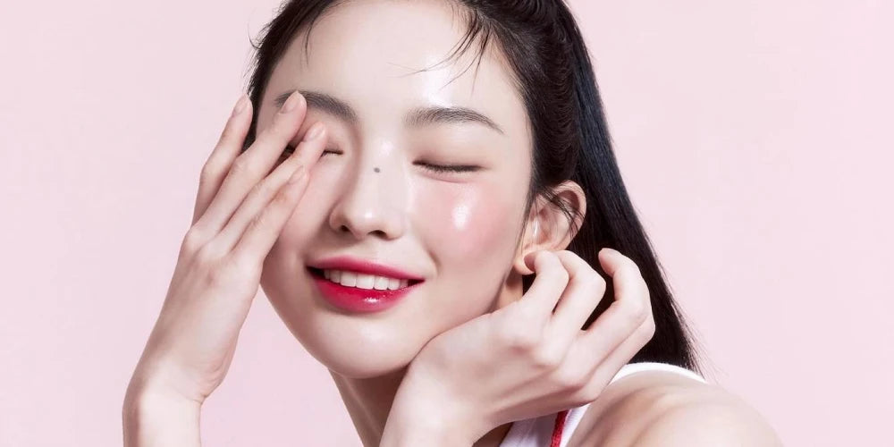 Modèle avec maquillage coréen typique : teint lumineux glass skin, blush rose estompé sur les pommettes et lèvres dégradées effet mordu.